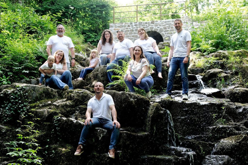 Rires et complicité pour cette grande famille réunie près d'une cascade en Normandie.