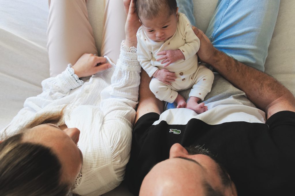 Un premier moment de tendresse et de complicité entre les parents et leur bébé lors d'un shooting en Normandie.